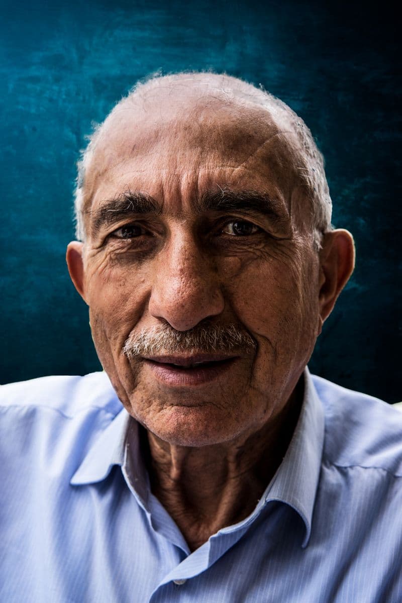 Portrait eines älteren Mannes mit grauem Schnurrbart vor blauem Hintergrund